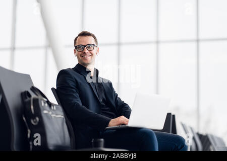 Working on laptop in airport while waiting for flight Stock Photo