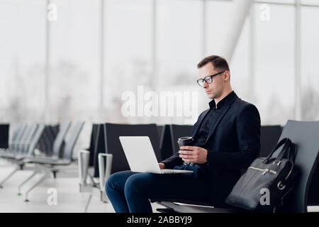 Working on laptop in airport while waiting for flight Stock Photo