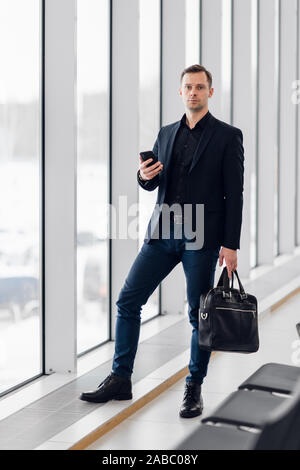 Business man using mobile phone app in airport. Young business professional man texting smartphone walking inside office building or airport terminal Stock Photo