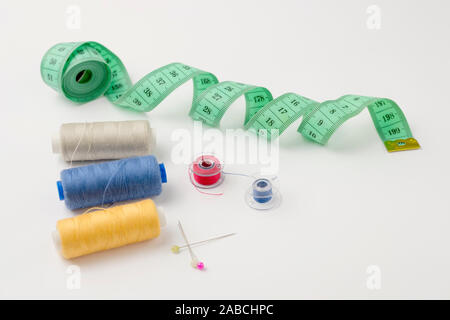 Sewing accessories on a white background. Centimeter tape, spools of thread, pins Stock Photo