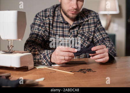 Tailor makes bow ties of woolen fabric. Work with sewing machine in a textile studio. Stock Photo
