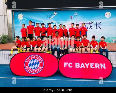 Retired Brazilian footballer Giovane Elber who played as a striker for Bayern Munich, middle, takes photos with students at Primary School Affiliated Stock Photo