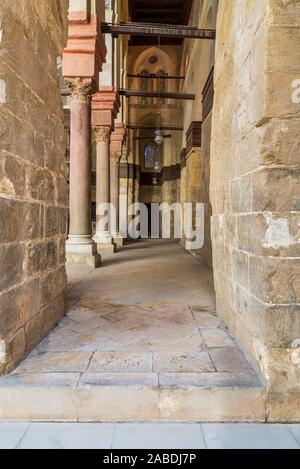 Passage at Sultan Qalawun Mosque with stone columns, colored stained glass windows and wooden door, Cairo, Egypt Stock Photo