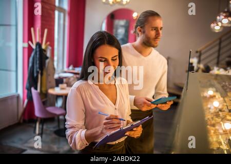 Businesswoman making notes while ordering foods with husband Stock Photo