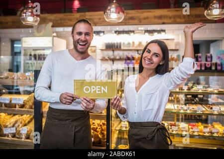 Husband and wife smiling broadly while opening their own bakery Stock Photo