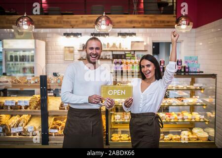 Cheerful couple feeling truly happy while opening their own bakery Stock Photo