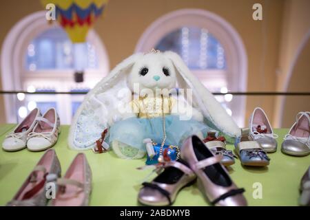 White fluffy hare toy among children's shoes, holiday decor in store Stock Photo