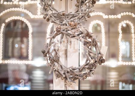 Christmas decor of branches and cones on the window against the background of shining lights garlands Stock Photo