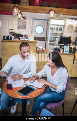 Couple feeling busy while working with documentation in their cafeteria Stock Photo