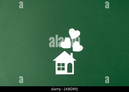 Home house, paper house with heart shape on green background. Family home and real estate concept. Flat lay, top view, copy space Stock Photo