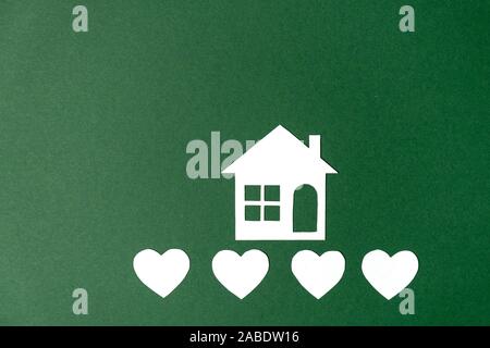 Family home and real estate concept. Home house, paper house with heart shape on green background. Flat lay, top view, copy space Stock Photo