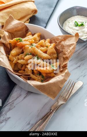 New England fried clam strips served with a bowl of tartar dipping sauce Stock Photo