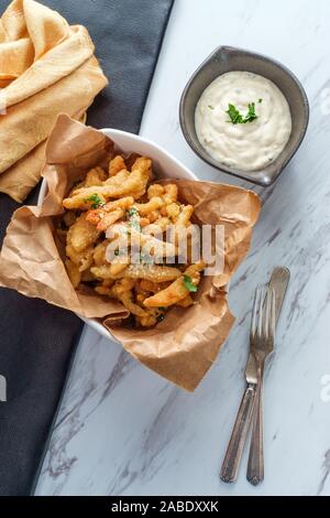 New England fried clam strips served with a bowl of tartar dipping sauce Stock Photo