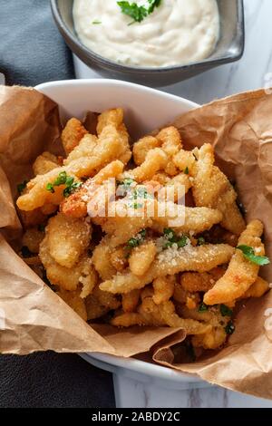 New England fried clam strips served with a bowl of tartar dipping sauce Stock Photo