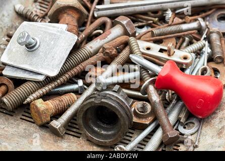 Metallic corroded  industrial waste: rusty bolts and nuts with red  screw driver on the top of the heap, close-up, copy space, recycle hardware backgr Stock Photo