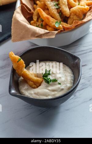 New England fried clam strips served with a bowl of tartar dipping sauce Stock Photo