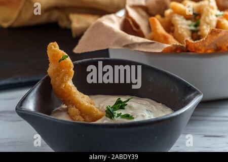 New England fried clam strips served with a bowl of tartar dipping sauce Stock Photo