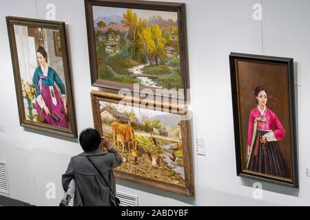 A visitor takes pictures of a piece of oil painting featuring a North Korean woman at the exhibition in Taiyuan city, north China's Shanxi province, 2 Stock Photo