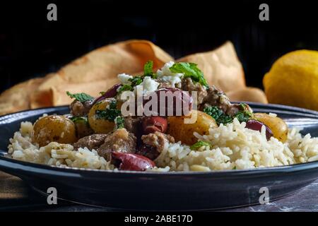Greek lamb stew marinated in a white wine salmoriglio sauce with new potatoes kalamata olives feta cheese and mint garnish Stock Photo