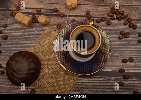 A Cup of coffee, marshmallows in chocolate, coffee beans, brown sugar on a wooden background. Close up Stock Photo