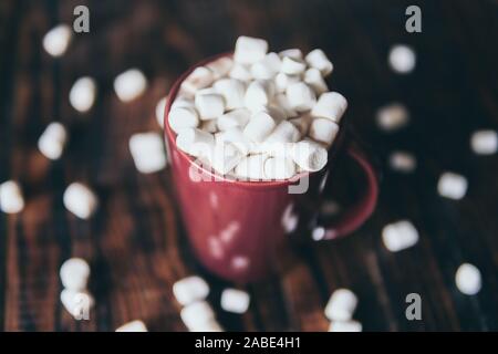 Close-up on hot chocolate mug covered with marshmallow on dark wood background Stock Photo
