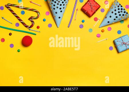 Birthday yellow background with party caps presents confetti candy. Copy space. Stock Photo