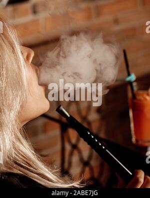 woman smoking hookah and blowing smoke at the restaurant Stock Photo