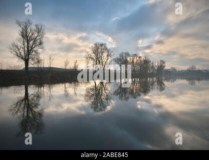 Calm autumn morning landscape with fog and warm sky over the pond surrounded by trees with the beautiful reflections of clouds and trees in the water Stock Photo