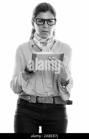 Studio shot of mature beautiful businesswoman standing while using digital tablet Stock Photo