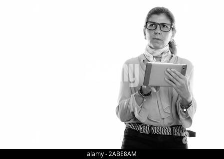Studio shot of mature beautiful businesswoman using digital tablet while thinking Stock Photo