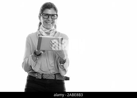 Studio shot of mature happy businesswoman smiling and using digital tablet Stock Photo