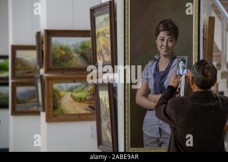 A visitor takes pictures of a piece of oil painting featuring a North Korean woman at the exhibition in Taiyuan city, north China's Shanxi province, 2 Stock Photo