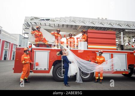 Fireman Jia Jie and his wife take unique pictures with the help of his colleagues in front of a fire fighting truck in Chengdu city, southwest China's Stock Photo