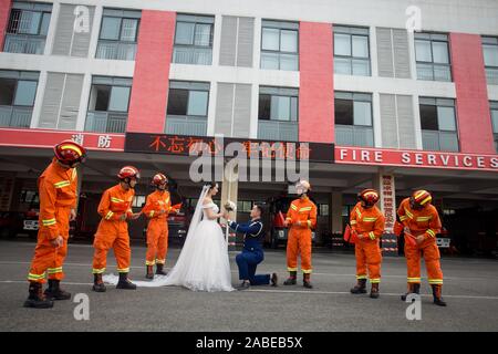 Fireman Jia Jie and his wife take unique pictures with the help of his colleagues in front of a fire fighting truck in Chengdu city, southwest China's Stock Photo