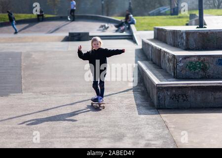 A cute little girl riding around the local skatepark on her skateboard, learning from the pro's around her Stock Photo