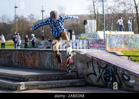 A cute little boy with ADHD, Autism, Asperger syndrome burns off energy at the Skateboard park, practicing tricks such as the ollie and jumping steps Stock Photo