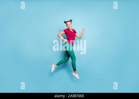 Full length body size photo of cheerful positive side profile girl wearing red t-shirt smiling toothily running for sales jumping up in trousers green Stock Photo