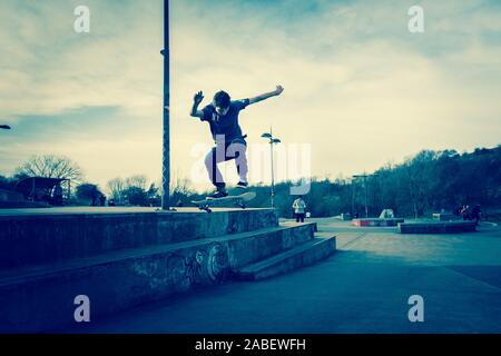 Skateboarders ollie off high steps onto the concrete below, dangerous adventure, extreme sports, professional skaters, Skateboarding Stock Photo