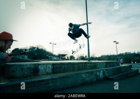 Skateboarders ollie off high steps onto the concrete below, dangerous adventure, extreme sports, professional skaters, Skateboarding Stock Photo