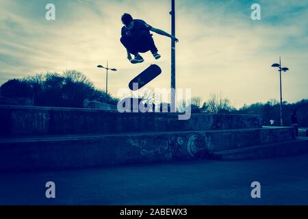 Skateboarders ollie off high steps onto the concrete below, dangerous adventure, extreme sports, professional skaters, Skateboarding Stock Photo