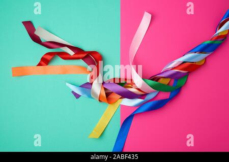 many silk multi-colored ribbons on a colored background, top view Stock Photo