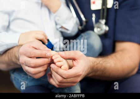 the pediatrician examines the child's feet, the dermatologist treats the heels, foot and heel massage.Concept of examination and treatment of children Stock Photo