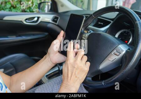 Women's hand holding a mobile phone in the car Stock Photo