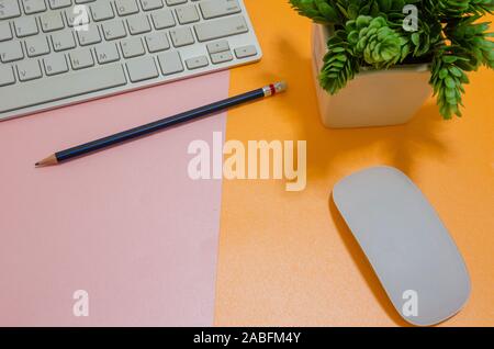 Computer keyboard and mouse and pencil on pink and orange paper Stock Photo