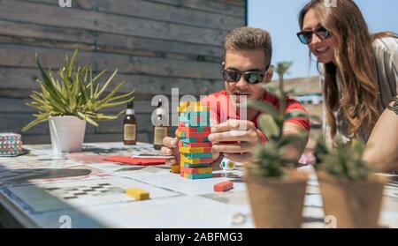 Man and woman playing with tower wooden on terrace Stock Photo