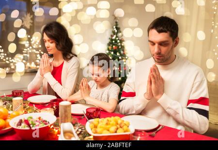 family praying before meal at christmas dinner Stock Photo