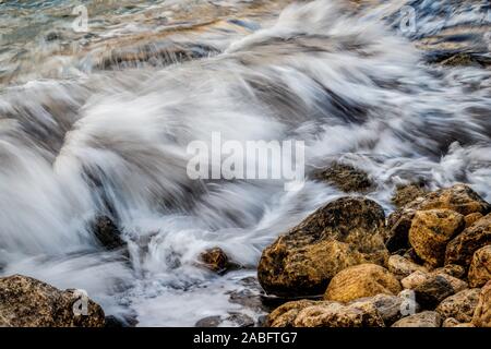 The sea breaking over shoreline rocks in Malta, EU. Long exposure times to show water movement. Stock Photo