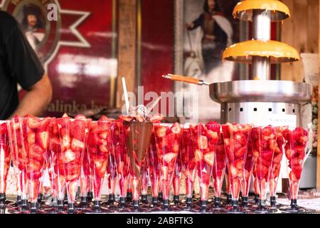 Budapest, Hungary - September 13, 2019: Adult couple Strawberry sugar coated skewers. Strawberry fruit on wooden skewers Stock Photo