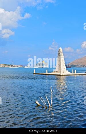 The Kolona obelisk dating from 1813, viewed from De Bosset Bridge, with Argostoli town waterfront in the background. Cruise liner moored at terminal. Stock Photo