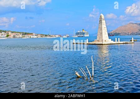 The Kolona obelisk dating from 1813, viewed from De Bosset Bridge, with Argostoli town waterfront in the background. Cruise liner moored at terminal. Stock Photo